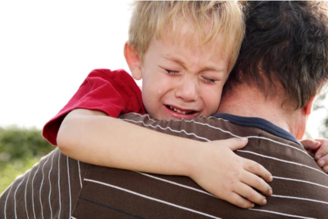 ילד קטן בוכה על זרועות אביו בריצה למרחב המוגן 